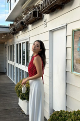 a lady in a red vest with white polka dots and a pair of white pants